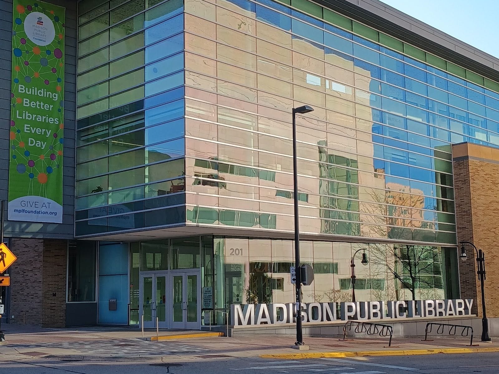 Modern Madison Public Library with large glass windows and a vibrant banner.