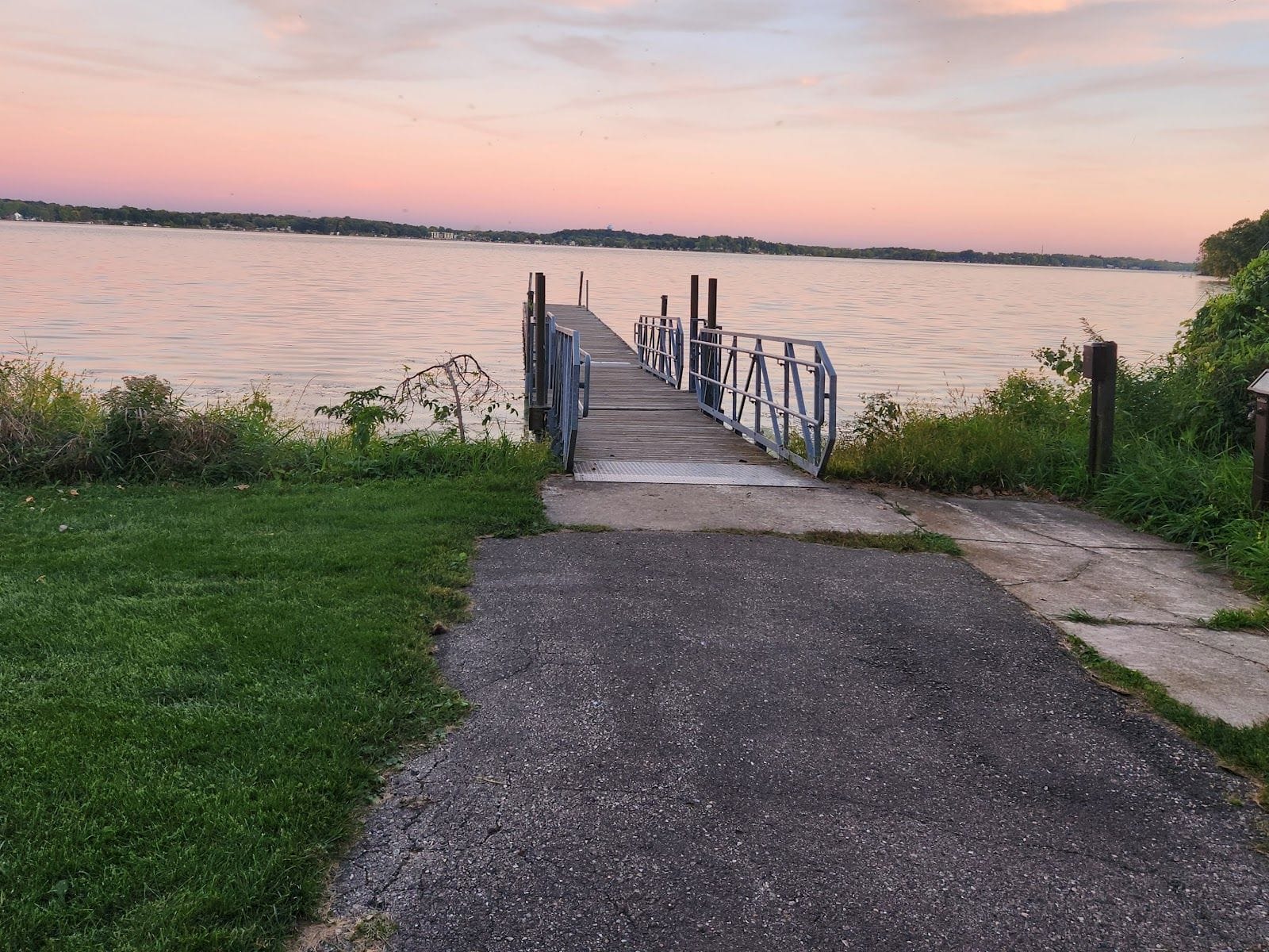Scenic view of a wooden dock extending into a calm river at sunset.
