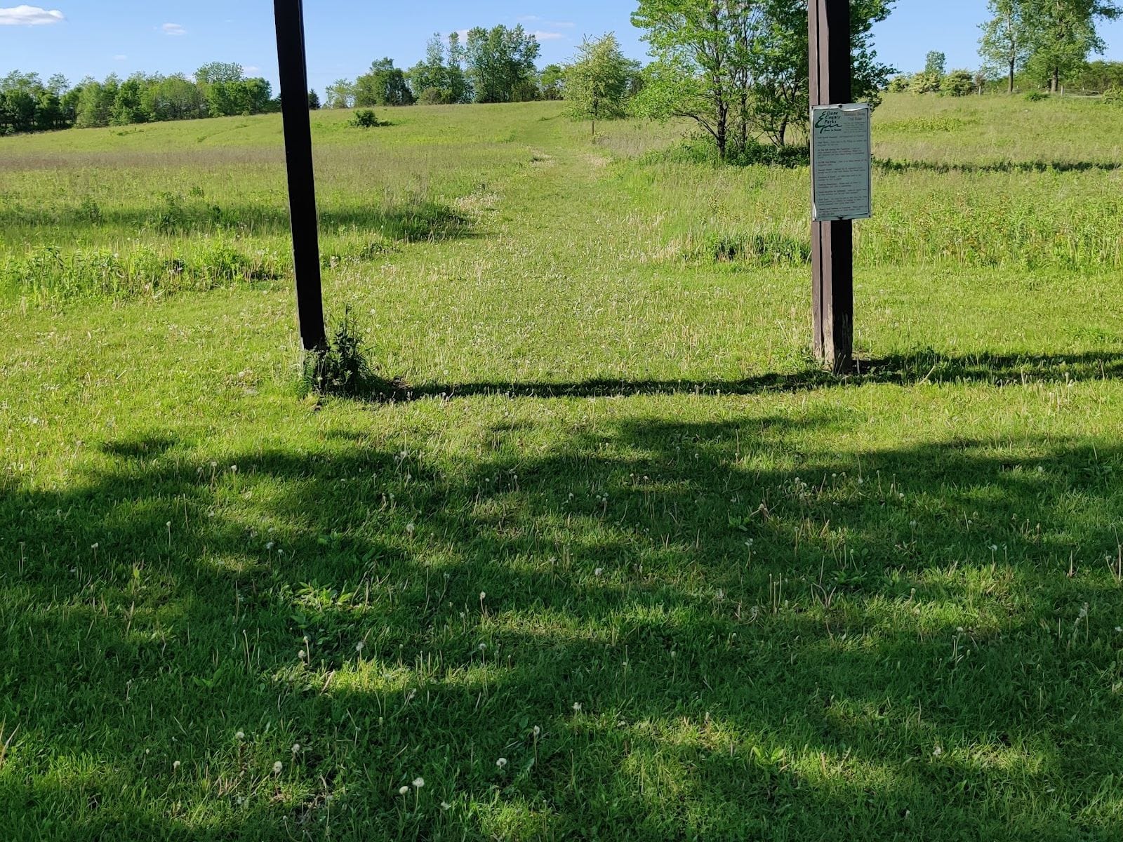 A grassy path leads into Badger Prairie County Park under a blue sky with scattered clouds.