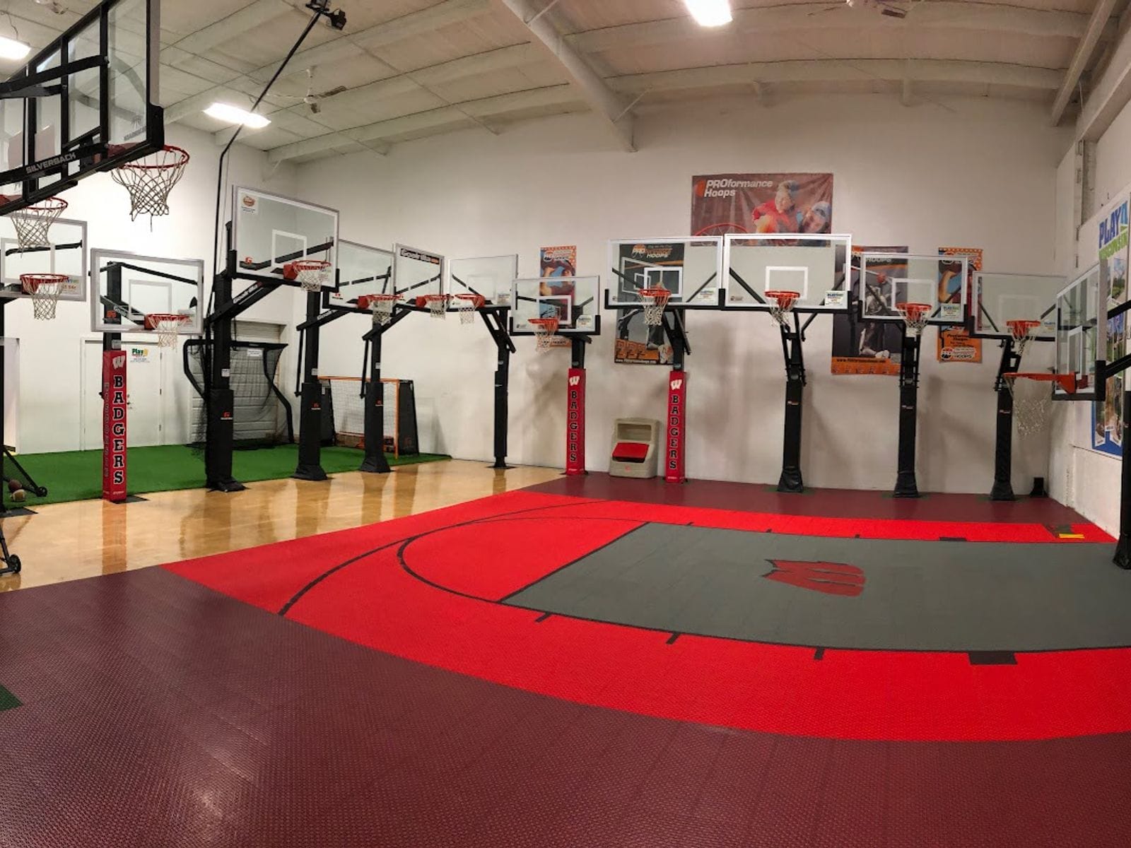 Indoor basketball court with multiple hoops and red flooring at PlayN Wisconsin.