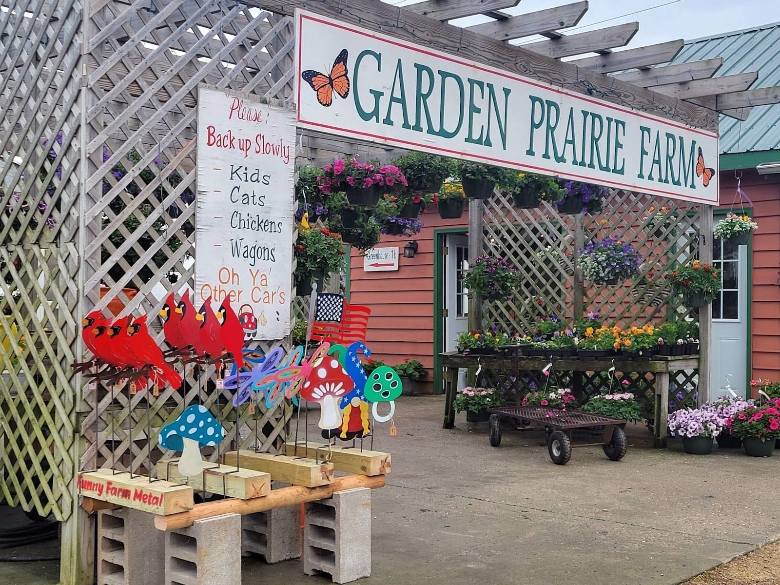 Flower baskets, playful signs, and garden art at the entrance of Garden Prairie Farm in Sun Prairie, WI.