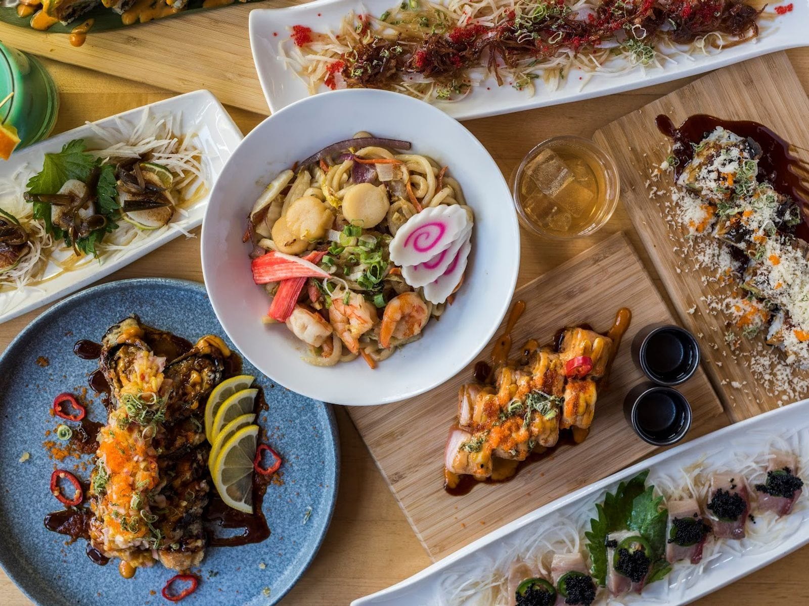 Colorful ramen bowl and assorted sushi plates arranged on a wooden table at Kawa Ramen and Sushi.