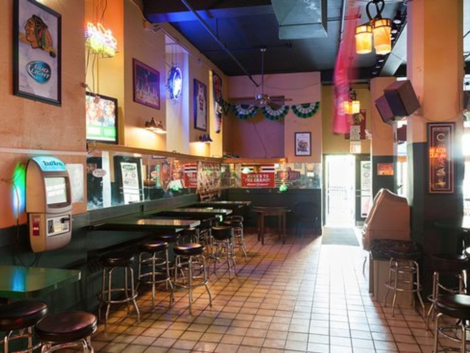 Cozy Chicago bar interior with barstools, neon signs, sports memorabilia, and tiled floors.