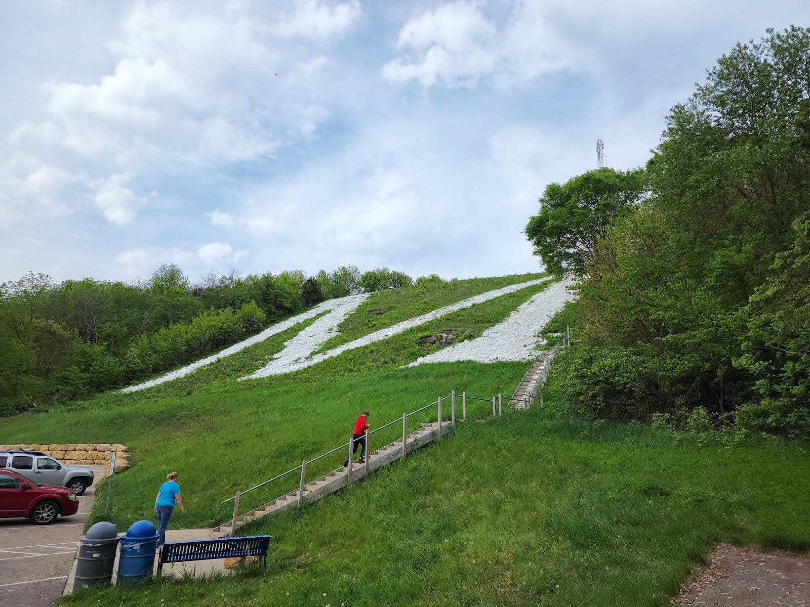 People climb steps toward the giant white Platte Mound “M” on a lush hillside in southwest Wisconsin.