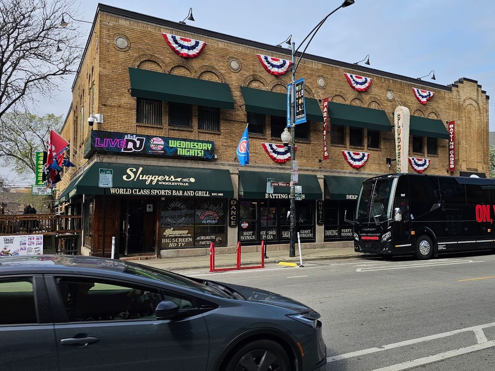Exterior of Sluggers sports bar with green awnings and festive red, white, and blue bunting.