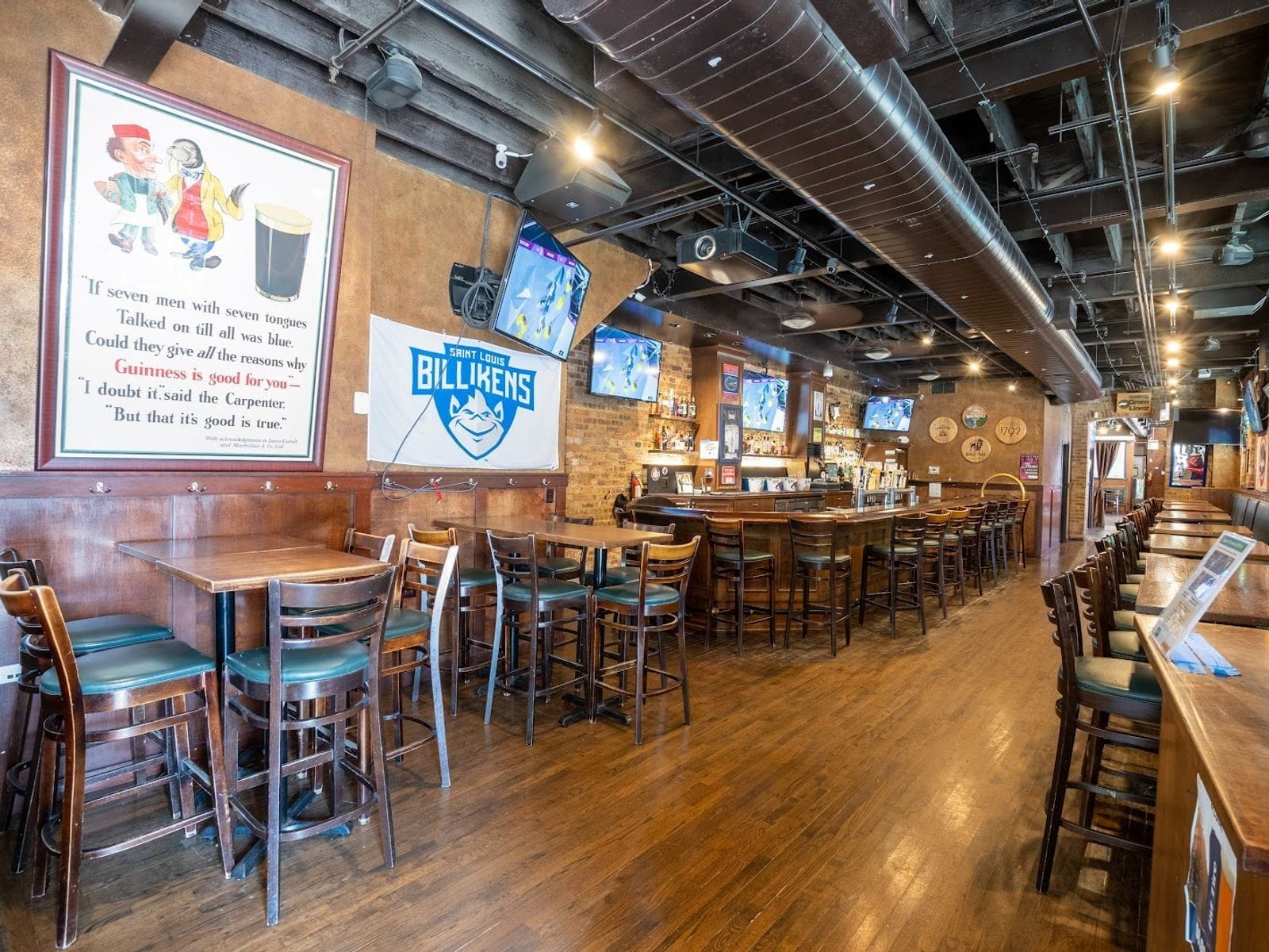 Spacious sports bar with wooden floors, high tables, TVs, and vibrant wall decor in Chicago.