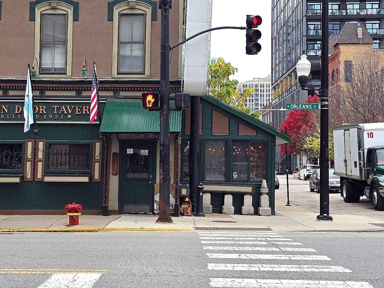 Historic Green Door Tavern with green awning, flags, and vintage windows on a city street corner.