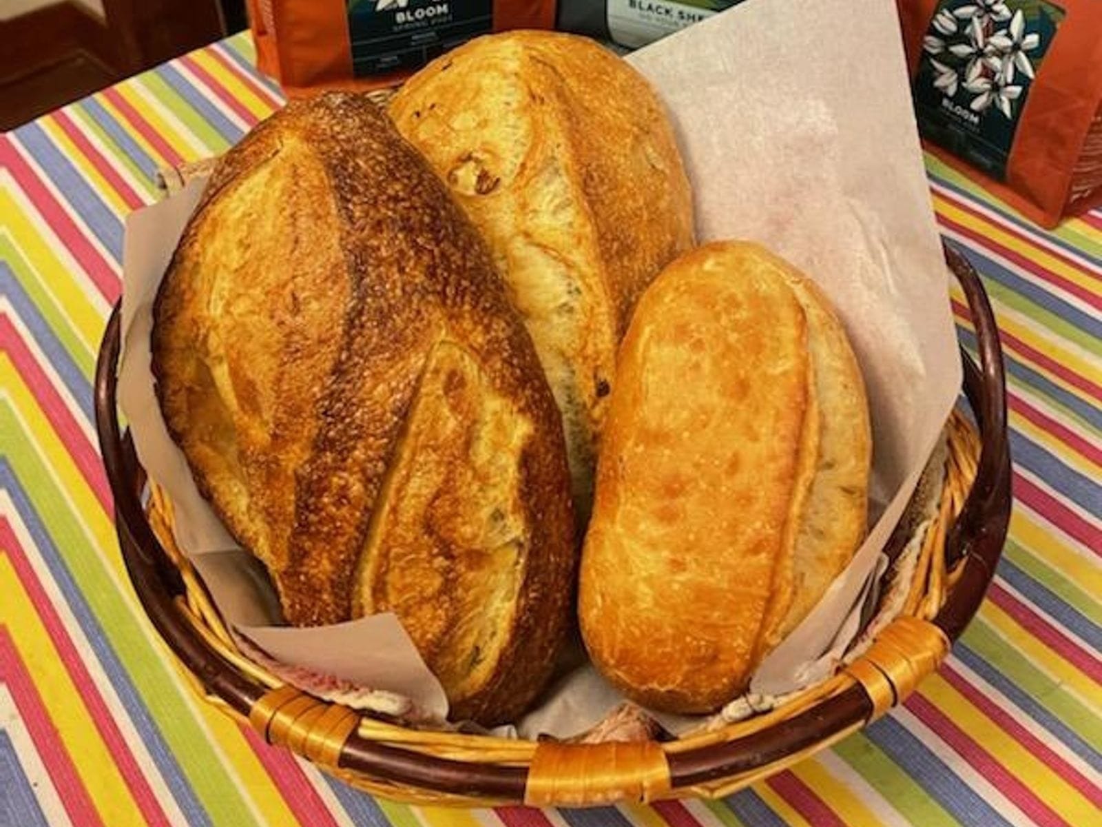 Basket with three golden artisan loaves on striped tablecloth at Windsor Breads Bakery & Coffee House.