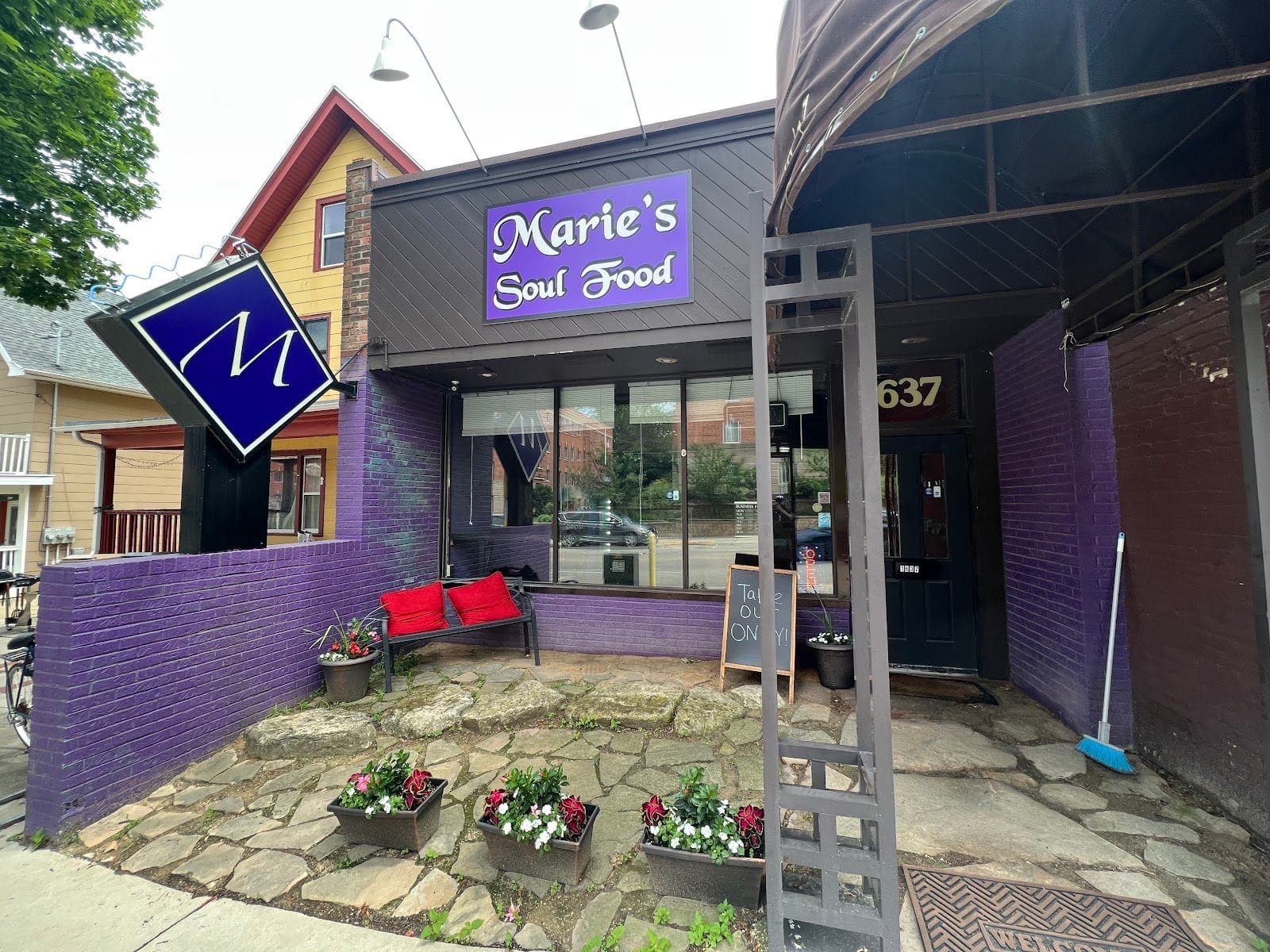 Purple-painted exterior of Marie’s Soul Food with a bench, potted flowers, and bold storefront sign.