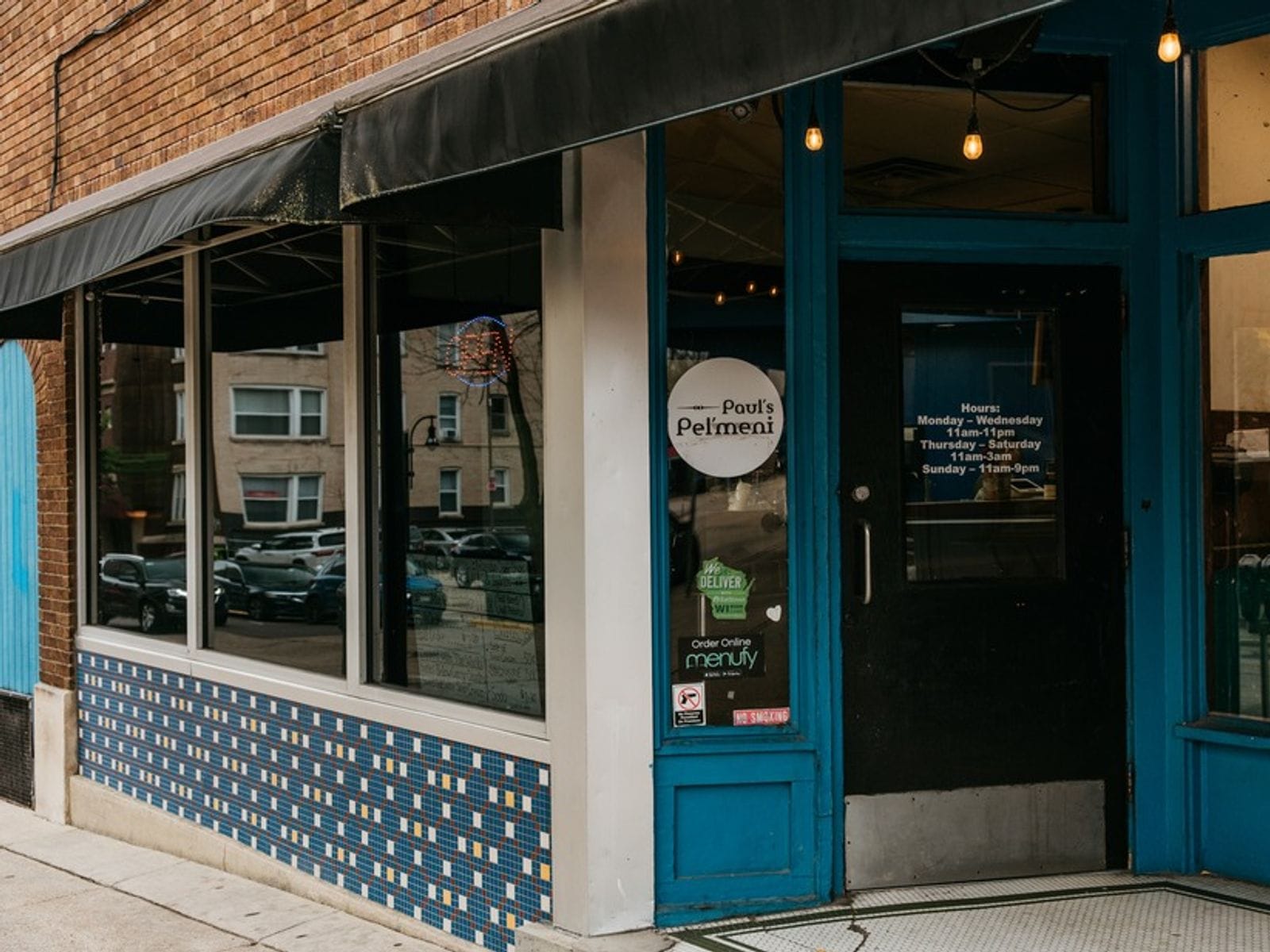 Brick building with blue trim, tiled exterior, and a glass door labeled "Paul's Pel'meni" restaurant.
