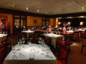 Elegant Italian restaurant dining room with white tablecloths, wine glasses, and soft ambient lighting.