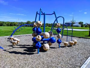 Colorful playground equipment surrounded by green grass under a clear blue sky.