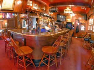Cozy, vintage-style bar interior with wooden stools, red carpet, and warm lighting at Swingin' Door Exchange.