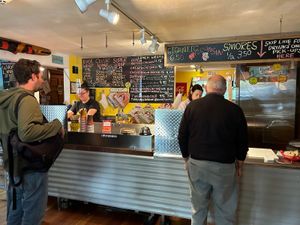 Customers order breakfast wraps and s'mores at a cozy eatery with colorful chalkboard menus.
