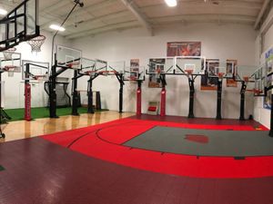 Indoor basketball court with multiple adjustable hoops and red flooring at PlayN Wisconsin.