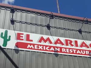 El Mariachi Mexican Restaurant sign with a green cactus on a gray exterior wall under blue sky.