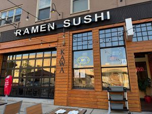 Exterior of Kawa Ramen and Sushi with wood paneling, large windows, and bold signage on a sunny day.