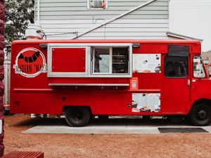 Bright red Modern Maki Sushi food truck with sushi logo and menu displayed on its side, parked outdoors.
