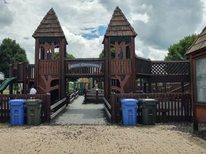 Large wooden playground structure with towers, ramps, and a "Kids' Crossing" sign at McKee Farms Park.
