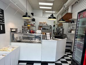 Counter at a casual eatery with a deli case, popcorn bins, menu board, and black-and-white checkered floor.