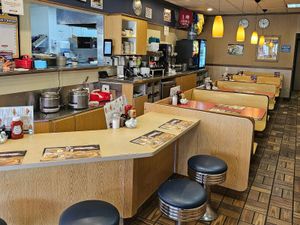 George Webb diner interior with counter stools, wooden booths, pendant lights and condiment bottles.