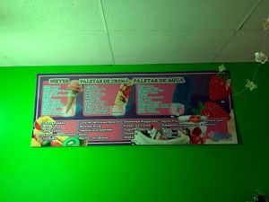 Paradise Ice Cream menu board on bright green wall showing cones, popsicles and fruit illustrations.