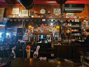 Swingin' Door Exchange wooden backbar with beer taps, rows of liquor bottles, vintage clock and framed photos.