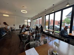 The Marquette Cafe interior: wooden tables, metal chairs, pendant lights and seated customers by large street-facing windows
