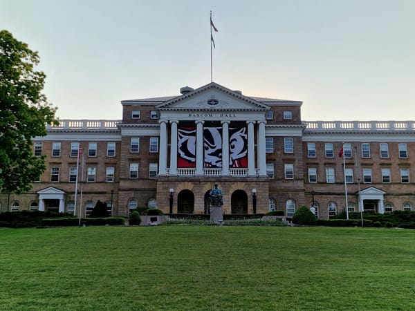 Bascom Hall at UW-Madison, showcasing its historic architecture and banners on a lush green lawn.