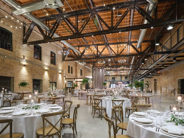 Industrial-chic interior of Garver Feed Mill, featuring elegant tables and lush greenery.