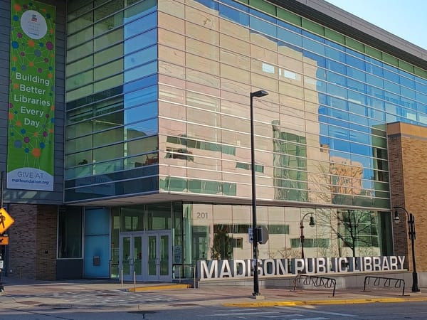 Modern Madison Public Library with large glass windows and a vibrant banner.