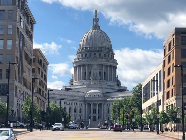 The Wisconsin State Capitol showcases its grand dome and Beaux-Arts architecture against a blue sky.