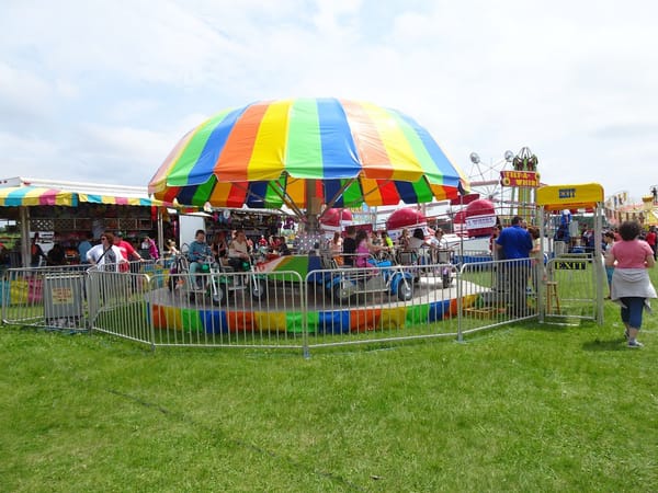 Colorful carousel and carnival stalls filled with families enjoying the festival atmosphere.