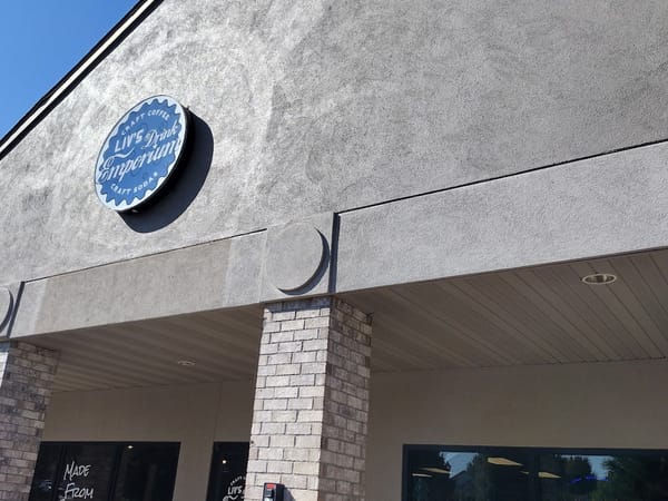 Sign for Liv's Drink Emporium featuring craft coffee and soda, with a modern facade.