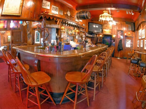 Cozy, vintage-style bar interior with wooden stools, red carpet, and warm lighting at Swingin' Door Exchange.