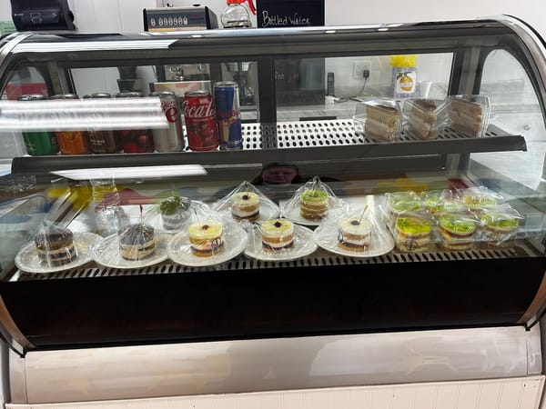 Dessert case with cakes, cheesecakes, and sodas at Dreamy Scoops, all individually wrapped for freshness.