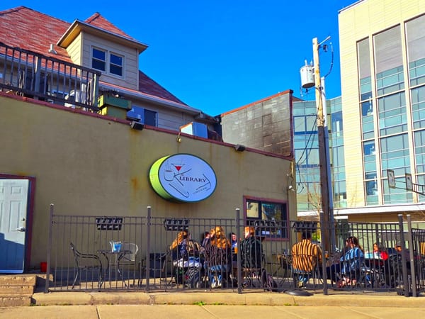Students gather at outdoor tables outside The Library Café near UW-Madison on a sunny day.