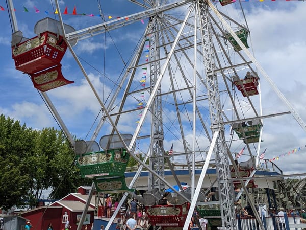 Ferris wheel with colorful cars and festive flags at a summer fair in Lake Mills, WI.