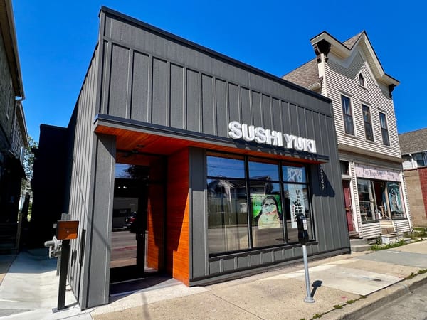 Modern exterior of Sushi Yuki restaurant with bright signage on a sunny day in Milwaukee, WI.